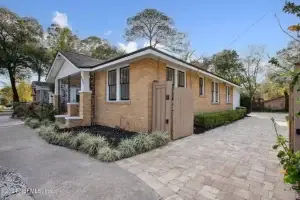 Front view of 4518 Astral Street, a renovated Norwegian brick home in Jacksonville, FL, featuring a landscaped yard and electronic gate.